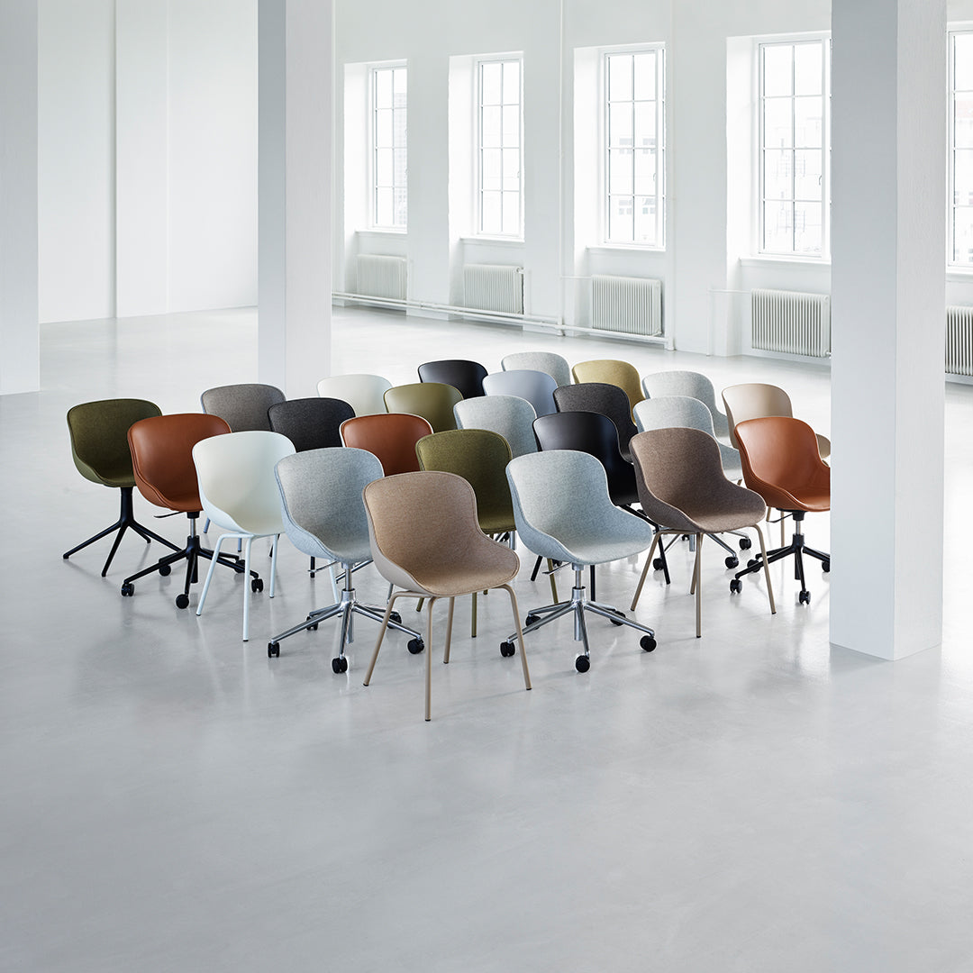 Collection of modern chairs in shades of blue, green, brown, and gray with smooth patterns on a light floor.