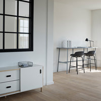 Modern white cabinet with black accents, light wooden floor, and neutral wall, showcasing minimalistic design and subtle patterns.