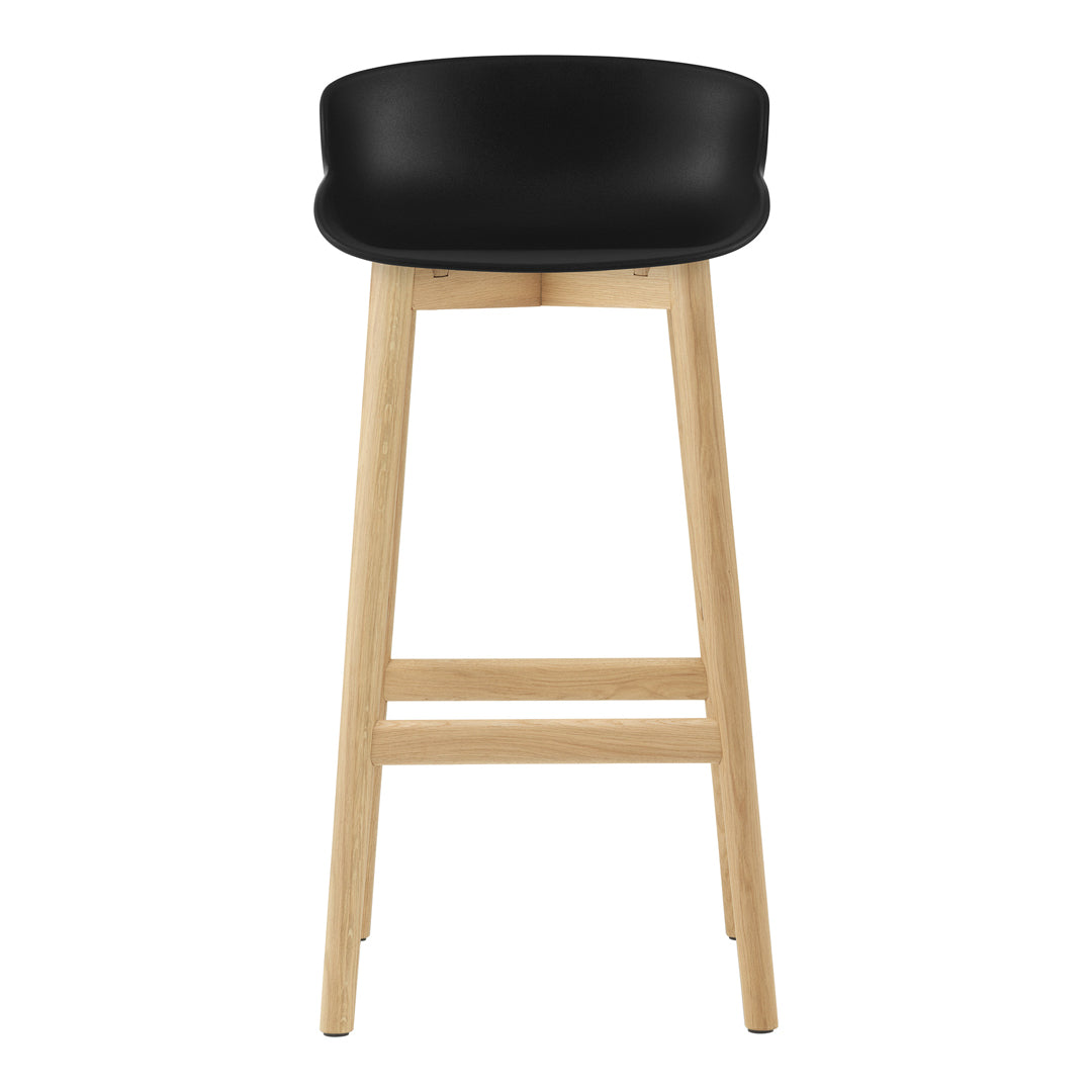 Black cushioned seat bar stool with natural wood legs, featuring a modern and minimalist design.