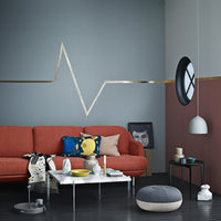 "Modern living room featuring a rust couch, geometric gold accents, and bold blue, gray, and burgundy wall patterns."