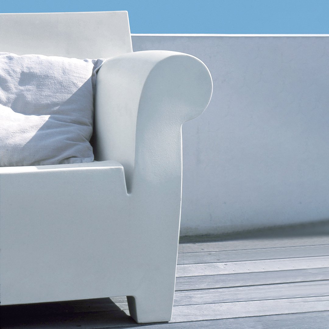White contemporary sofa arm with smooth curves, complemented by a light gray cushion against a blue sky background.