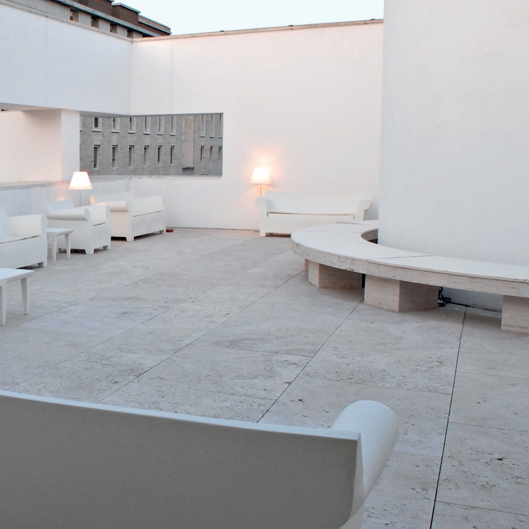 Stylish white patio furniture on a light stone floor, perfect for modern outdoor spaces.