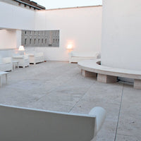 Modern outdoor patio featuring white furniture, smooth beige stone flooring, and minimalist design elements.