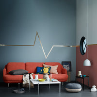 Stylish orange couch with gray and teal walls, featuring a sleek gold line accent and colorful decorative pillows.