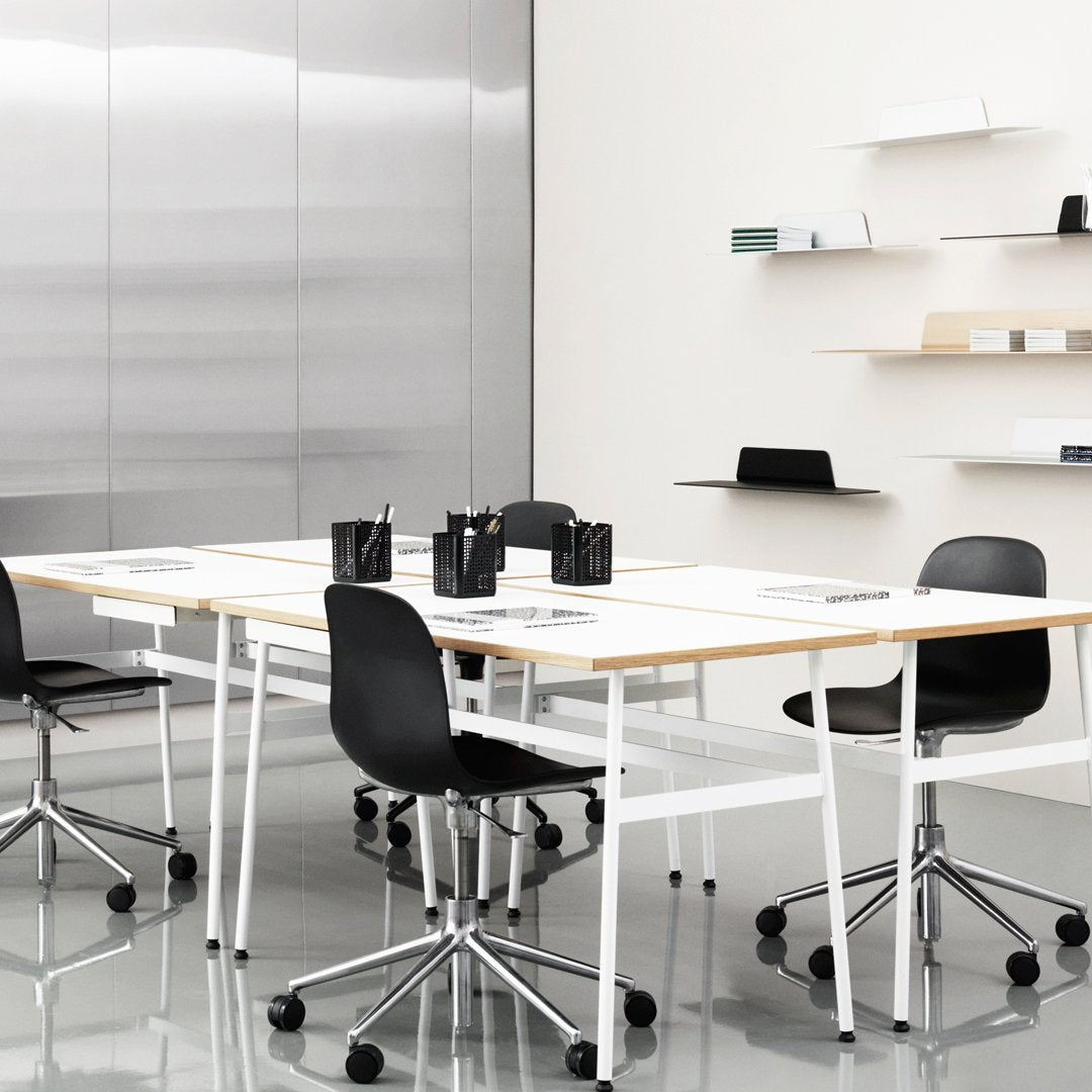 Modern office setting with a sleek white table, black rolling chairs, and minimalist decor, showcasing a monochrome color scheme.