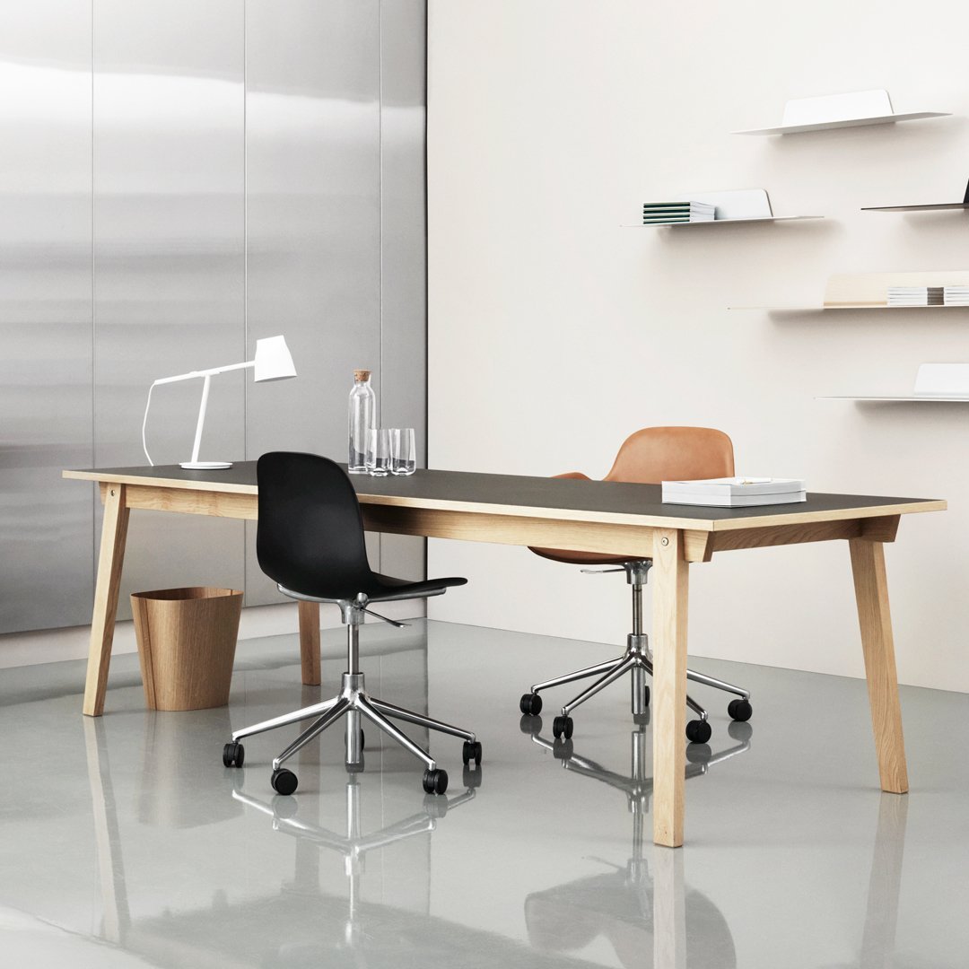 Modern office setup featuring a natural wood desk, black and tan chairs, and a sleek, minimalist aesthetic.