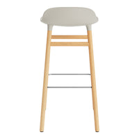 Gray padded seat bar stool with natural wood legs and a sleek metal footrest. Minimalist design with subtle colors.