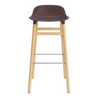 Brown molded seat with natural wood legs and a silver footrest, featuring a sleek, minimalist design.