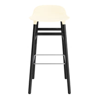 Cream-colored seat with sleek black wooden legs and a silver footrest. Modern minimalist design.