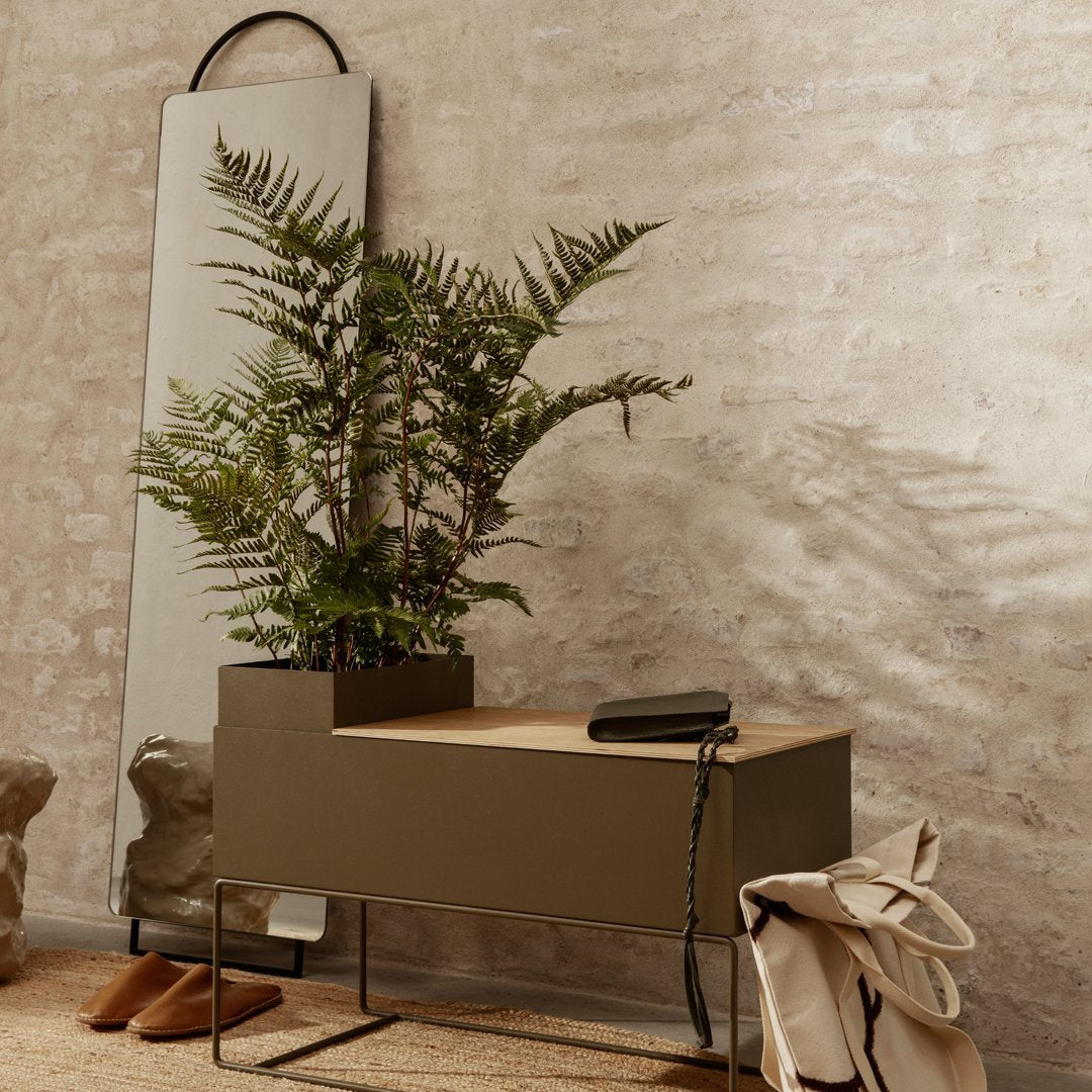"Olive green planter box with natural wood top, complemented by lush green fern and neutral-toned decor elements."
