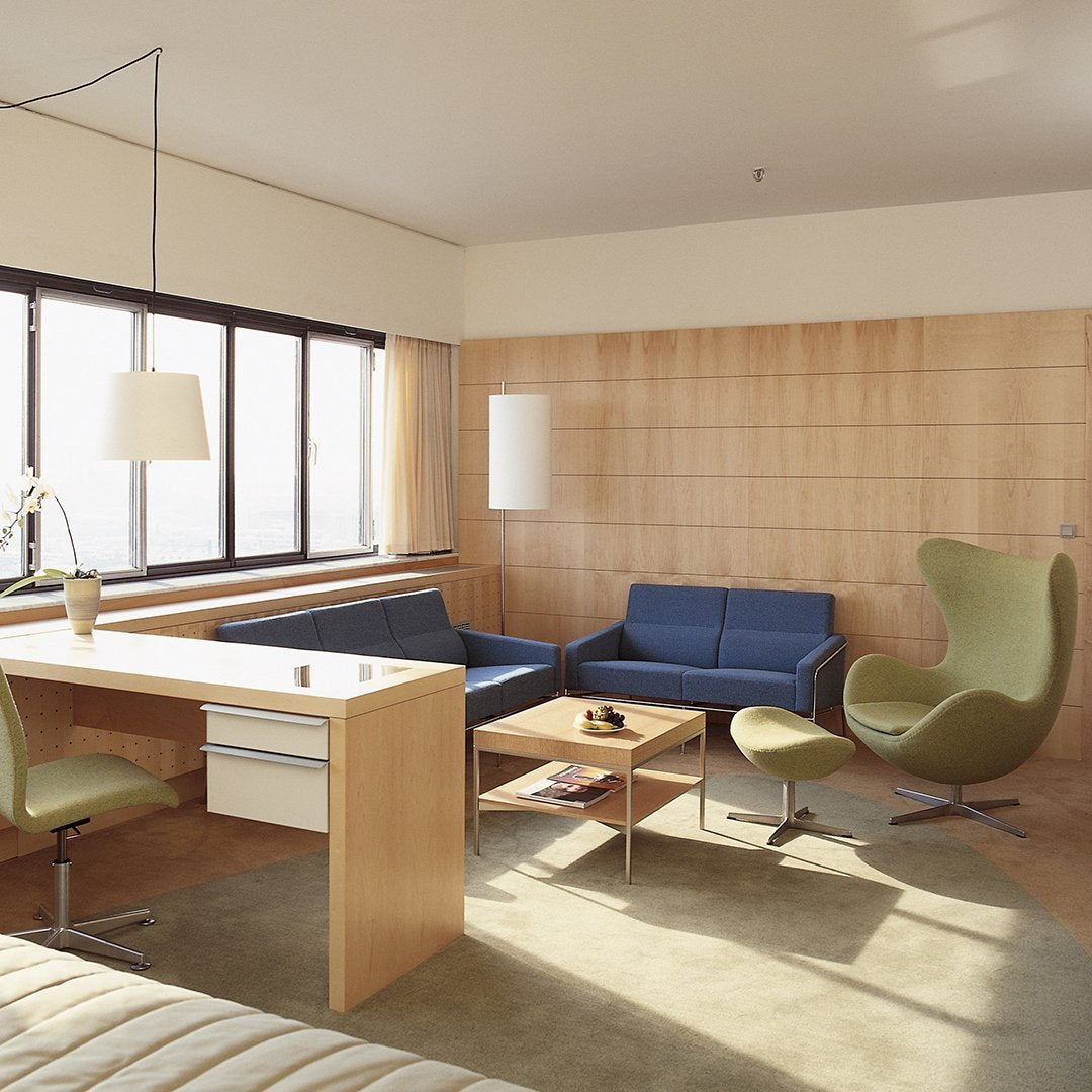 Modern living room featuring blue and green furniture with light wood accents and soft beige carpet.
