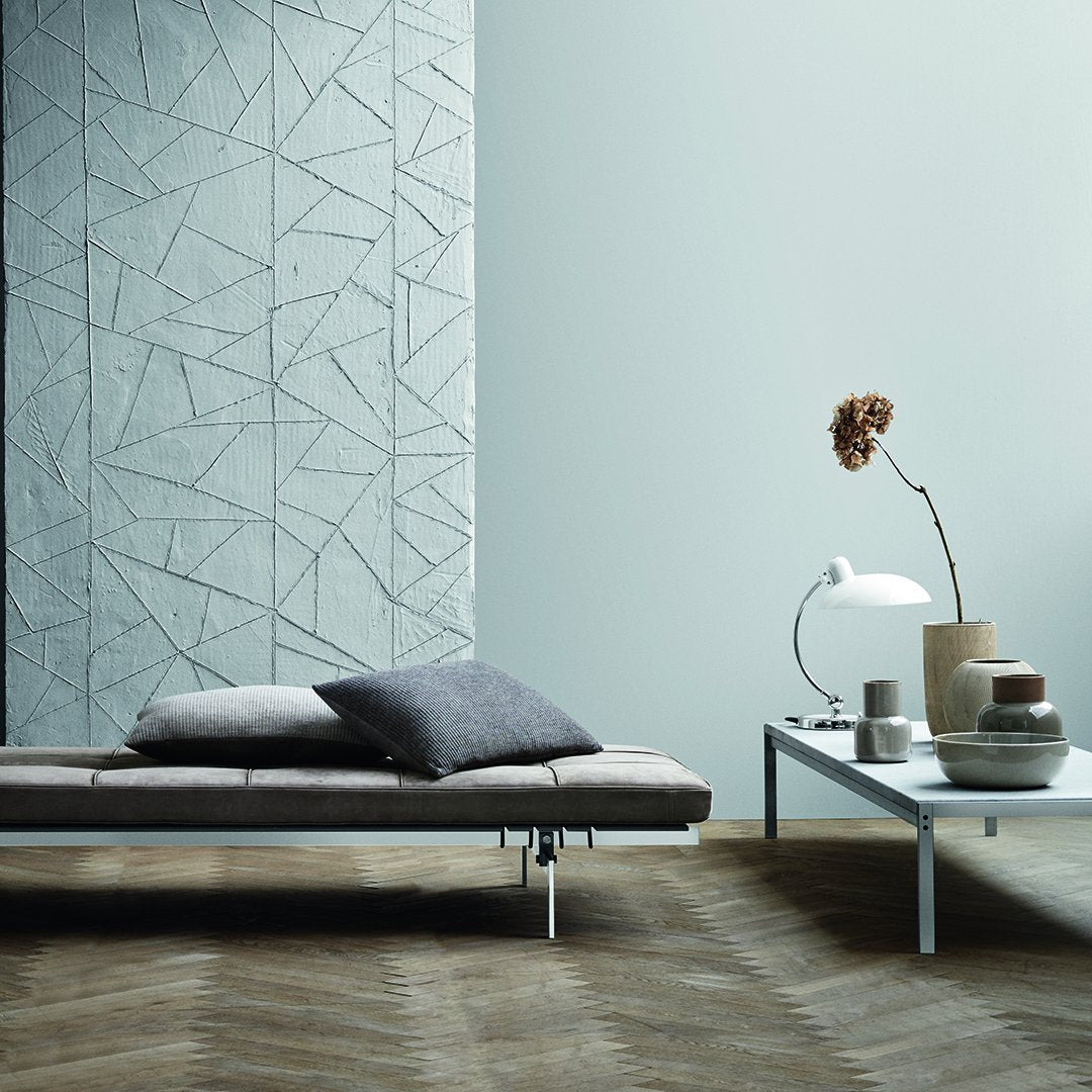 Gray geometric wall pattern, soft gray cushions, and polished wood flooring create a modern, minimalist aesthetic.