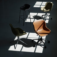 Four stylish chairs in olive green, black, warm brown, and cream, with sleek modern designs casting shadows.