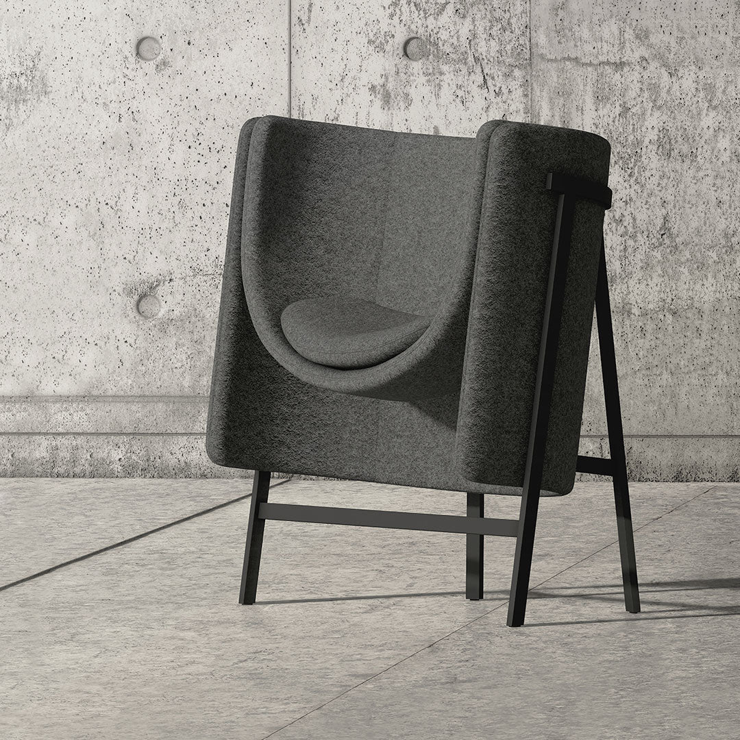 Stylish grey chair with smooth curved lines, contrasted by black metal legs against a textured concrete backdrop.