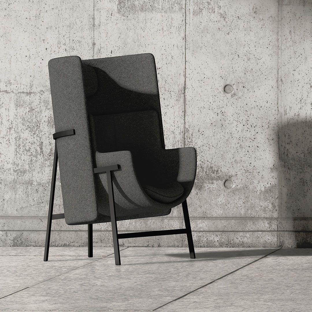 Gray upholstered chair with a sleek, minimalist design and contrasting black metal legs against a concrete backdrop.