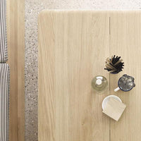Light oak table with a smooth finish, featuring black and white striped patterns in the background.