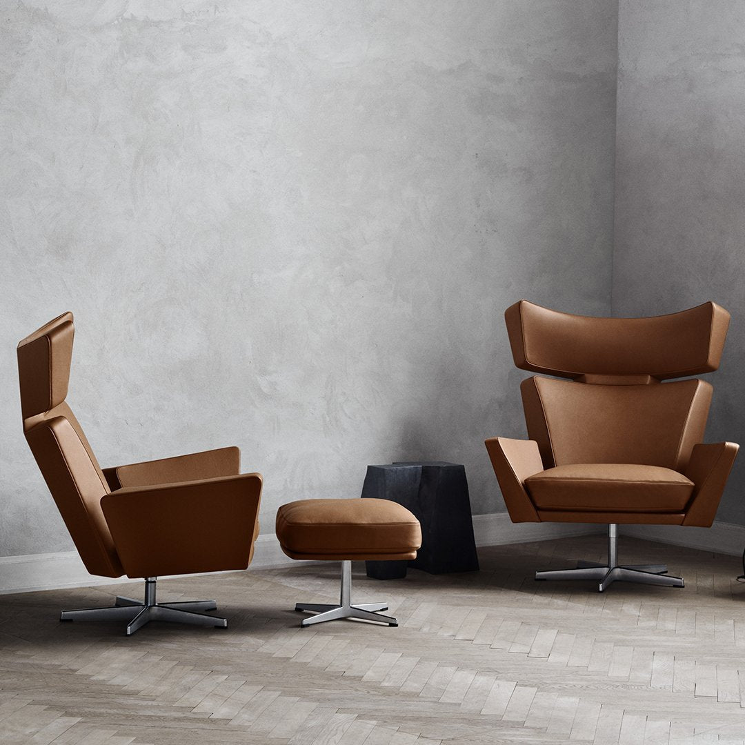Brown upholstered chairs with sleek, modern designs and circular bases, set against a neutral gray wall.