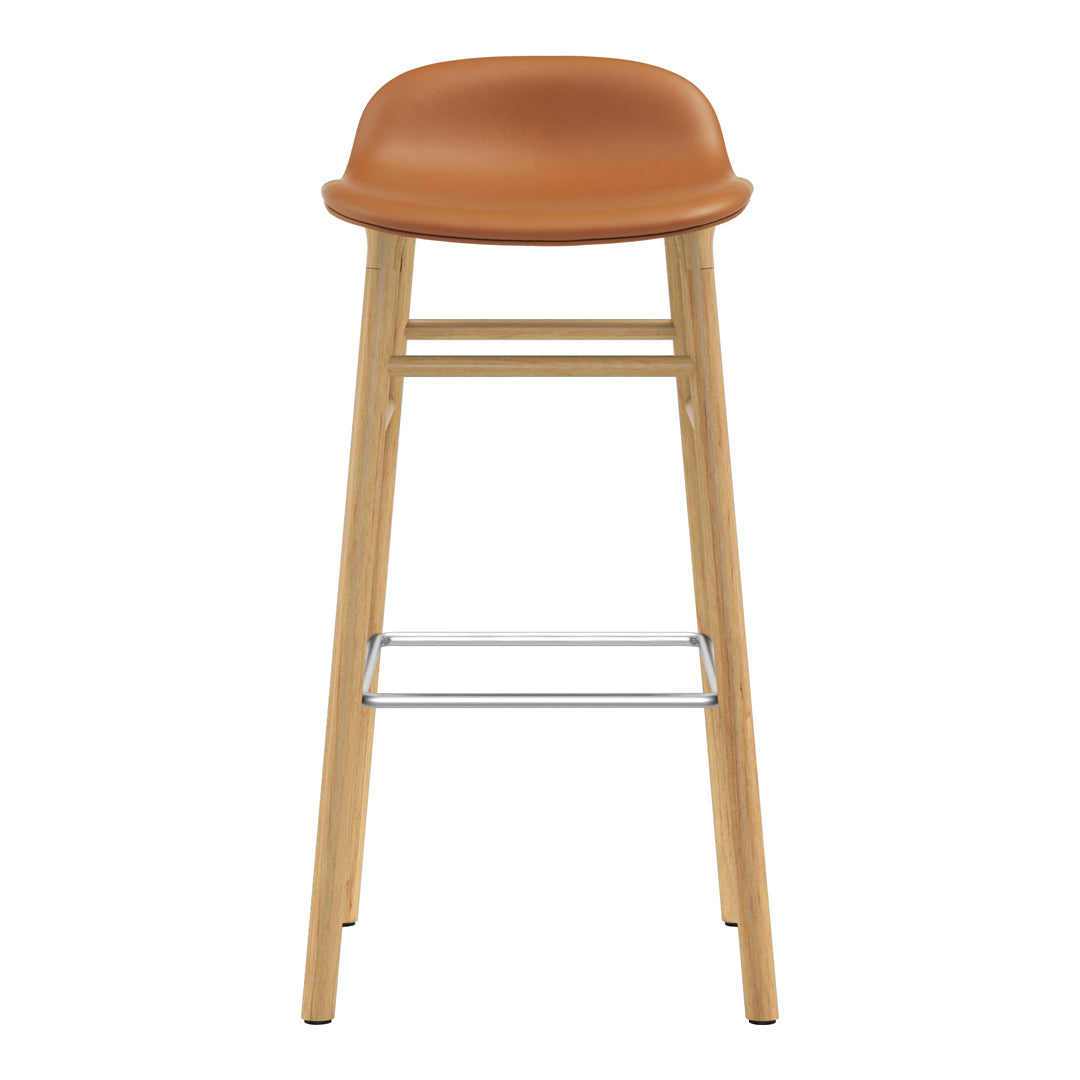 Tan leather seat with wooden legs and chrome footrest, featuring a minimalist and modern design.