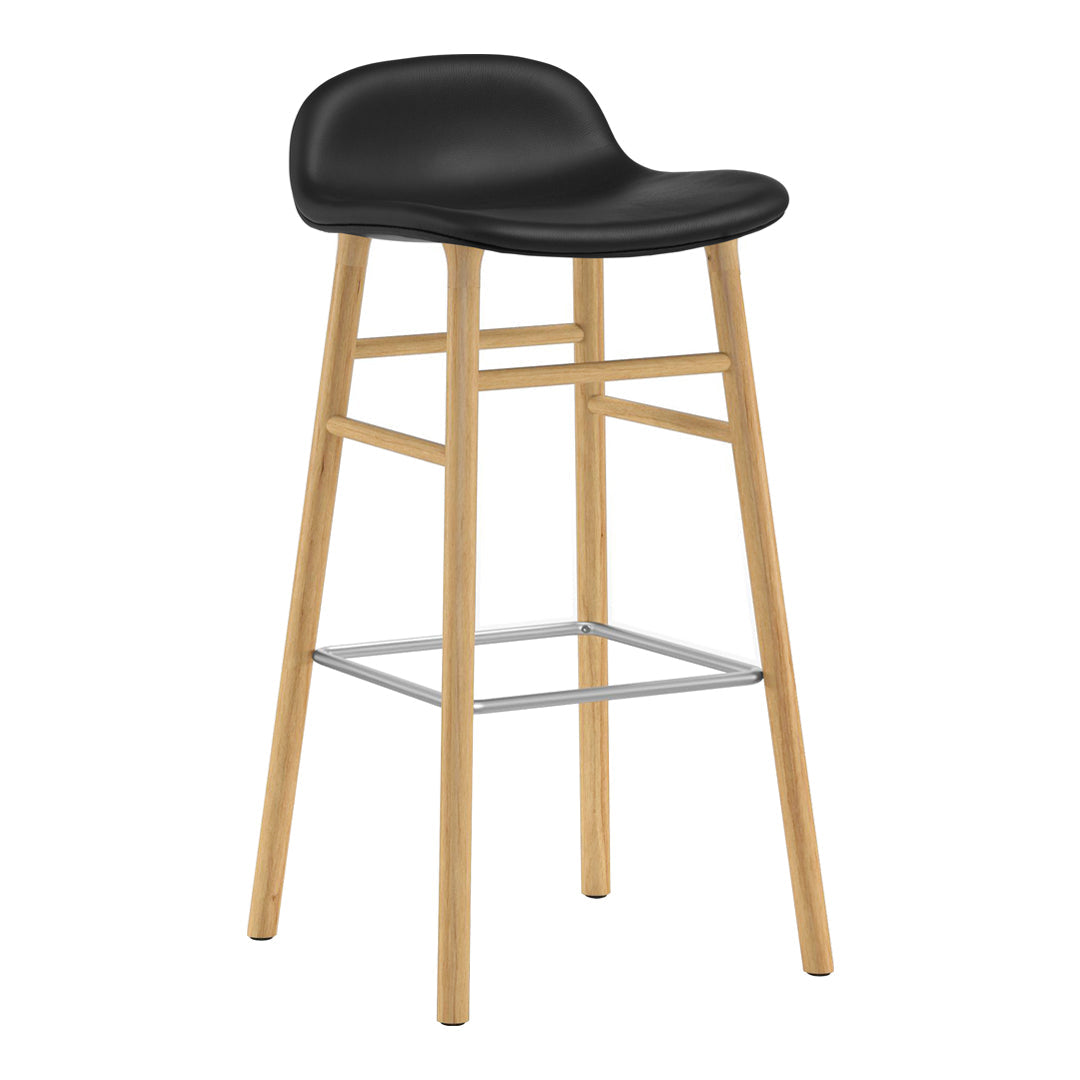 Black upholstered bar stool with natural wood legs and a sleek silver footrest. Modern design with a minimalist aesthetic.