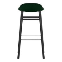"Green upholstered bar stool with a sleek black wooden frame and silver footrest."
