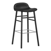 Black upholstered bar stool with a minimalist design and wooden legs, featuring a sleek, modern silhouette.