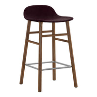 Burgundy upholstered stool with natural wood legs and chrome footrest, featuring a smooth, sleek design.