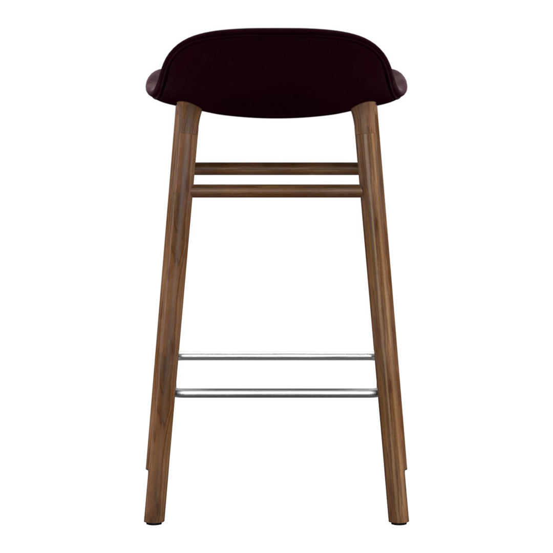 Burgundy upholstered bar stool with wooden legs and silver footrest, featuring a sleek, modern design.
