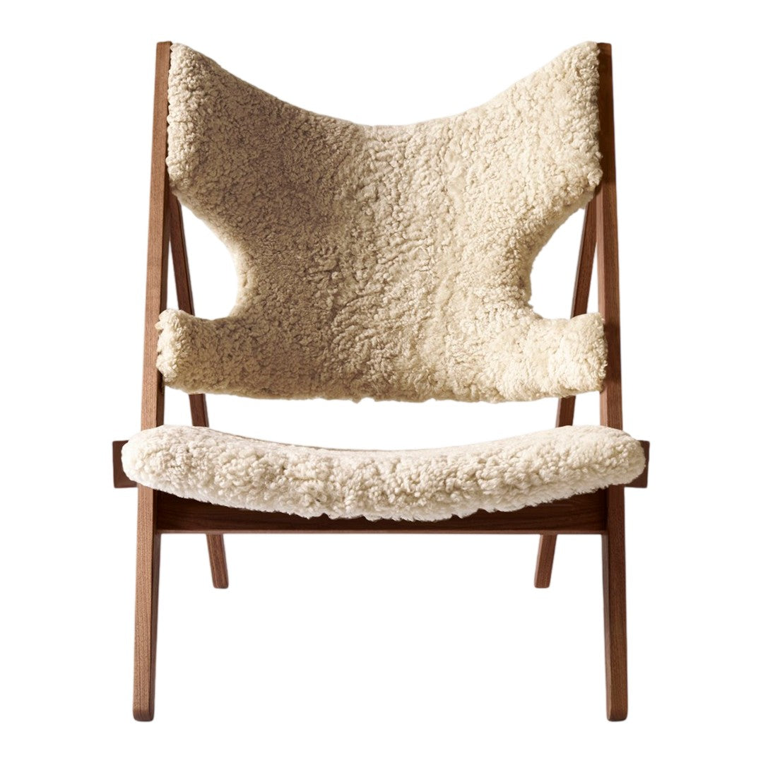 Cream-colored, textured sheepskin seat cushion with a wooden frame, featuring organic, minimalist design.
