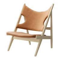 Tan leather lounge chair with minimalist wood frame, featuring smooth surfaces and clean lines for a modern look.