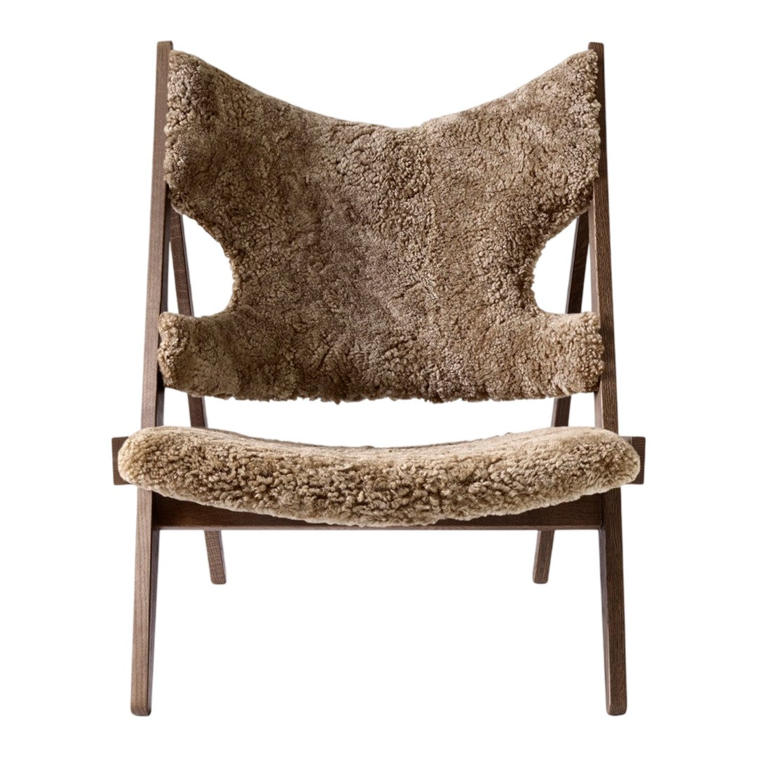 Beige shearling upholstery on a mid-century modern chair with a natural wood frame. Stylish and cozy design.