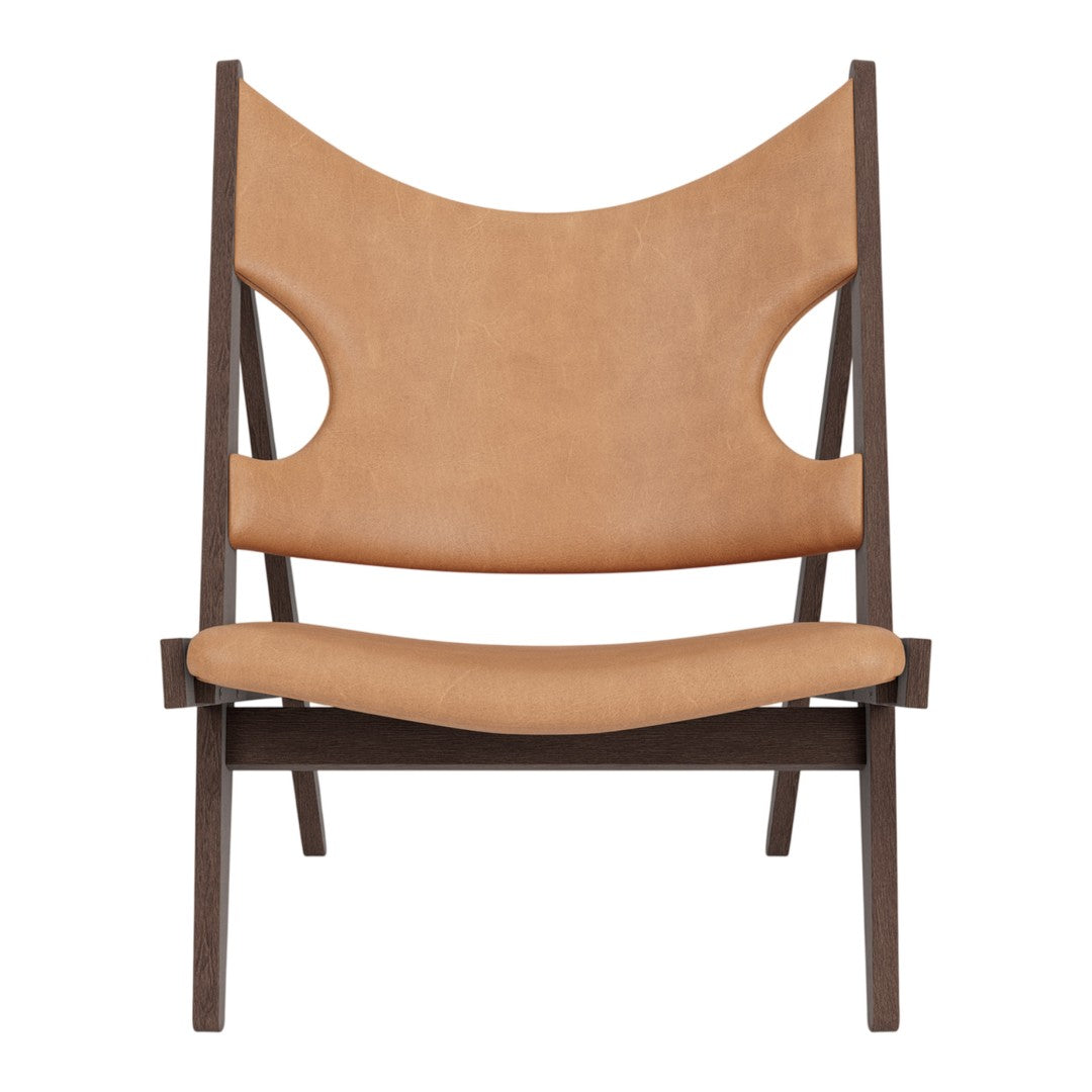 Tan leather chair with unique cut-out details and a dark wood frame, featuring a minimalist, modern design.