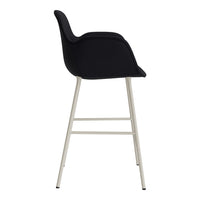 Black upholstered bar stool with sleek silver legs, featuring a minimalist design and smooth curves.