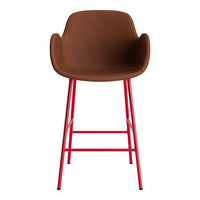 Brown upholstered bar stool with sleek red metal legs, featuring a modern, minimalist design.