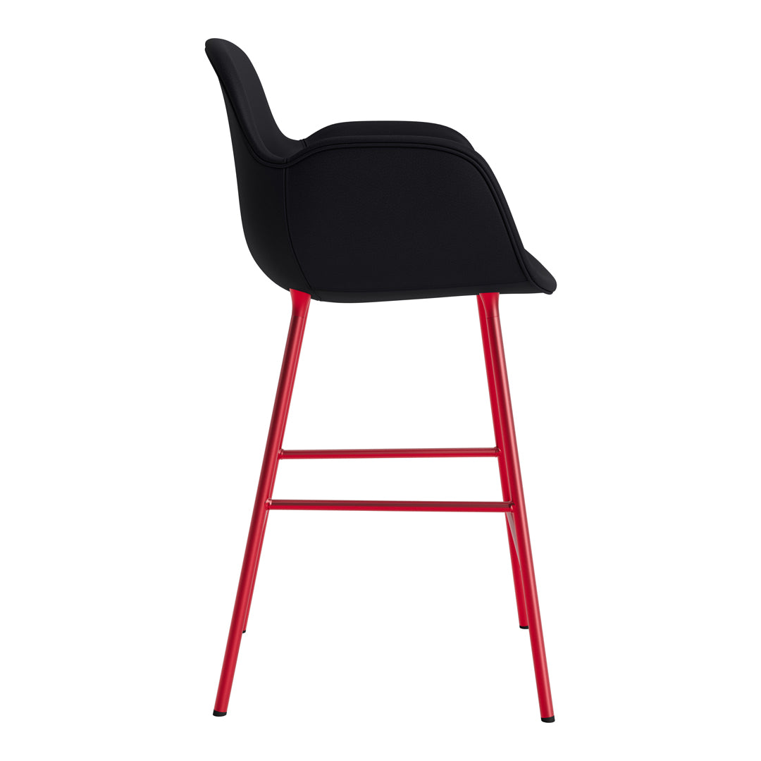 Black upholstered bar stool with sleek lines and vibrant red metal legs. Modern design for stylish interiors.