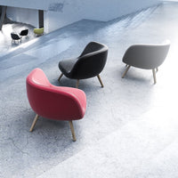 Colorful modern chairs in red, black, and gray with smooth curves and wooden legs on a minimalist floor.
