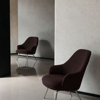 Sleek brown armchair with a smooth fabric, modern design, and chrome legs against a minimalist backdrop.