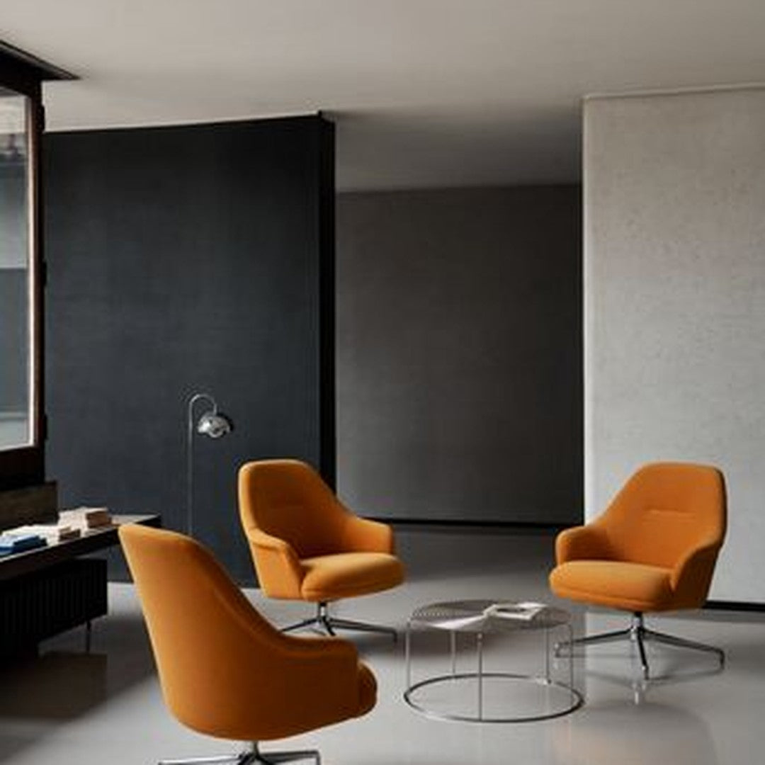 Orange modern chairs in a minimalist setting with black and gray walls. Sleek silver coffee table complements the design.