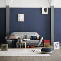 Gray sofa with colorful cushions, navy blue wall, light wood floor, and accent decor in warm tones and geometric patterns.