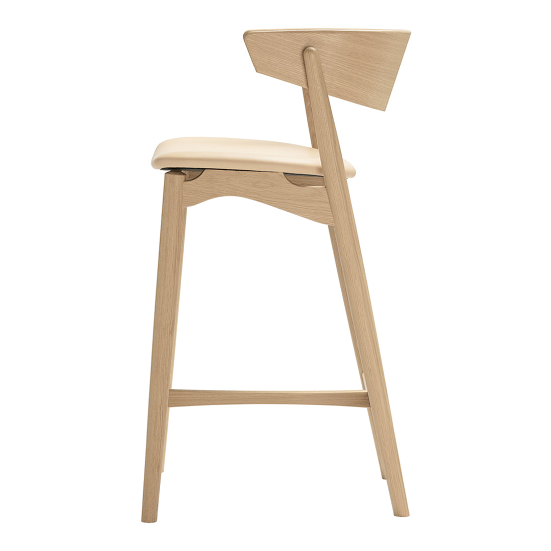 "Light wood bar stool with a smooth cream seat and a minimalist design, showcasing natural texture and soft curves."