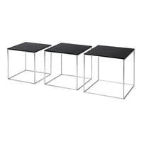 Set of three modern side tables with sleek black tops and minimalistic silver metal frames. Geometric design accents.