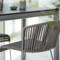 Gray woven dining chair with sleek lines, set against a minimalist backdrop. Perfect modern accent for any space.