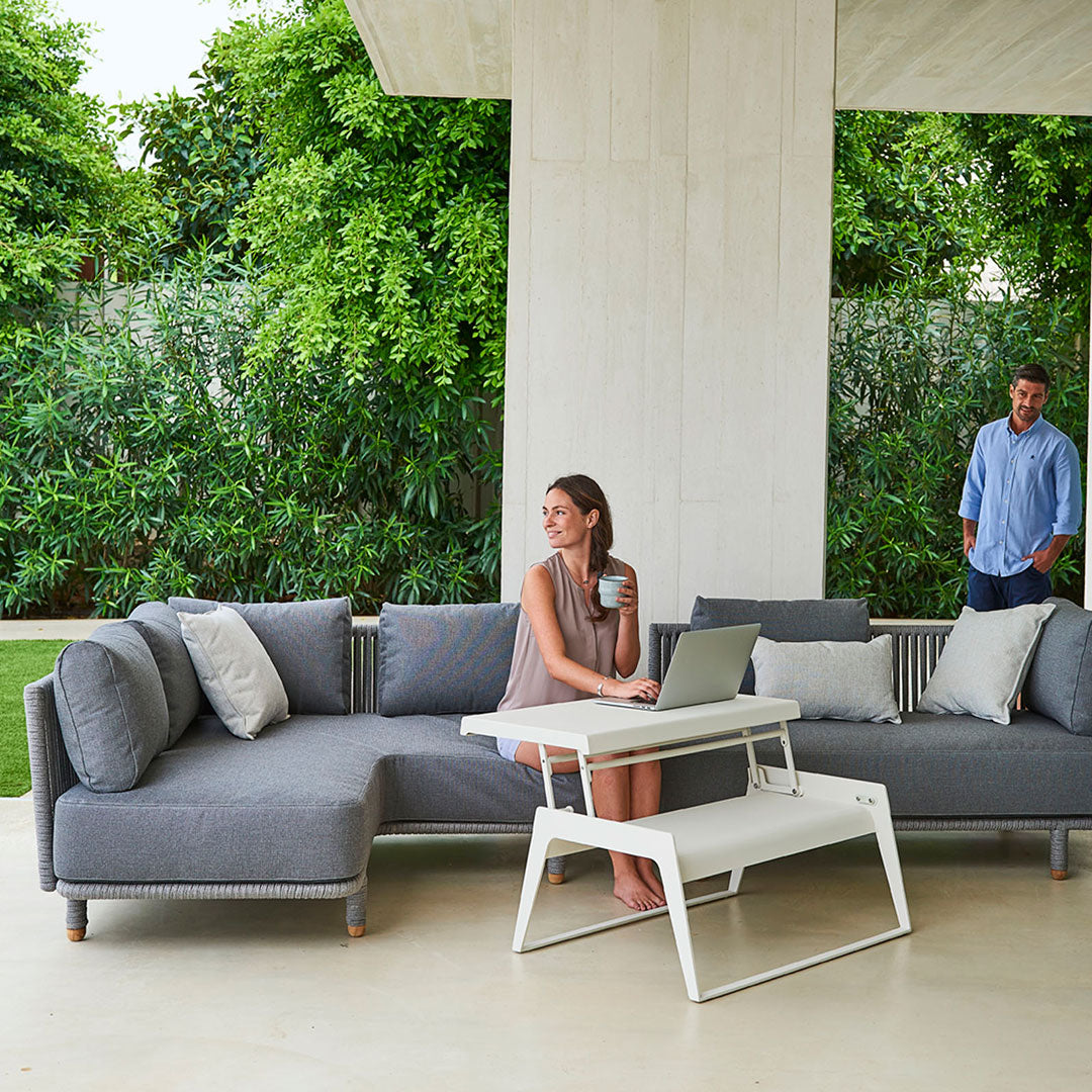 Modern gray sectional sofa with white accents and decorative pillows in a vibrant outdoor setting.