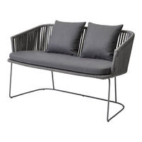 Gray woven loveseat with two matching cushions, featuring a sleek, modern design and minimalist metal legs.