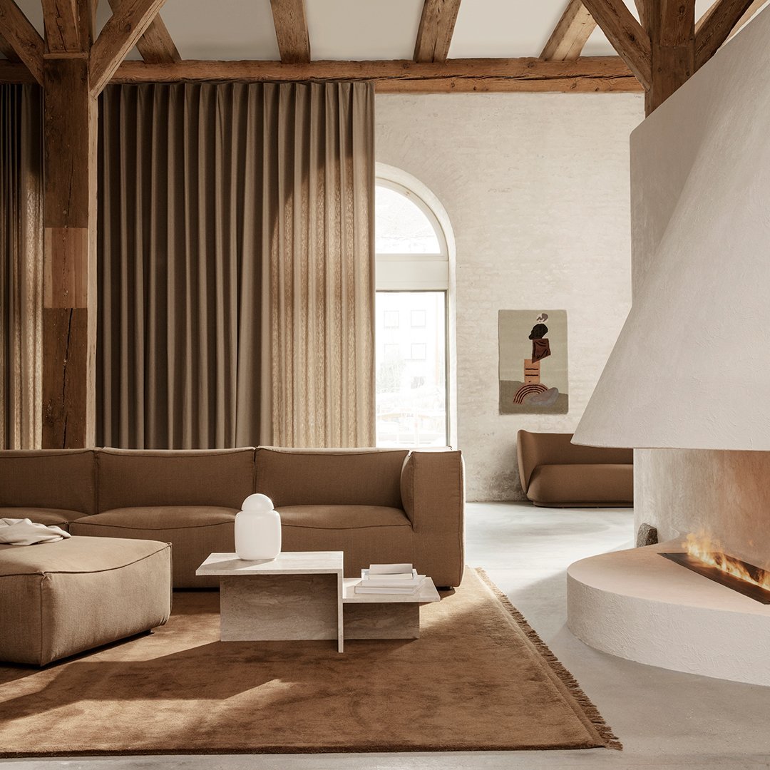 Cozy living room with earthy brown tones, textured beige curtains, and a minimalist white coffee table.