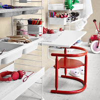 Bright red chair paired with a sleek white desk; colorful art supplies and playful decor enhance the design.