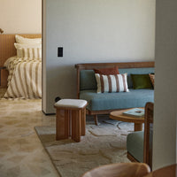 "Soft teal sofa with striped and solid pillows, warm wood accents, neutral tones in a cozy, textured living space."