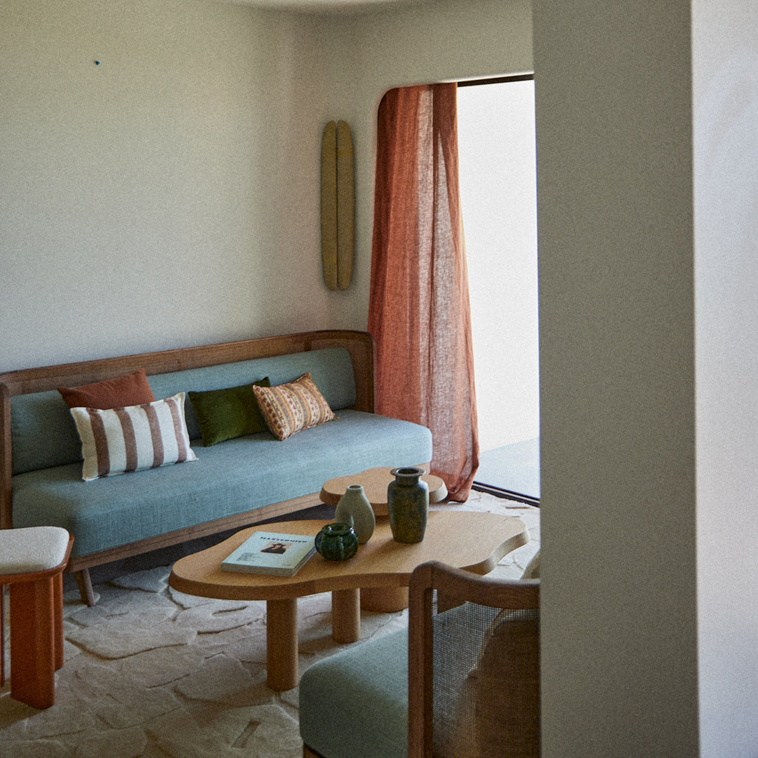 Contemporary living room with muted teal sofa, orange curtains, striped pillows, and natural wood accents.