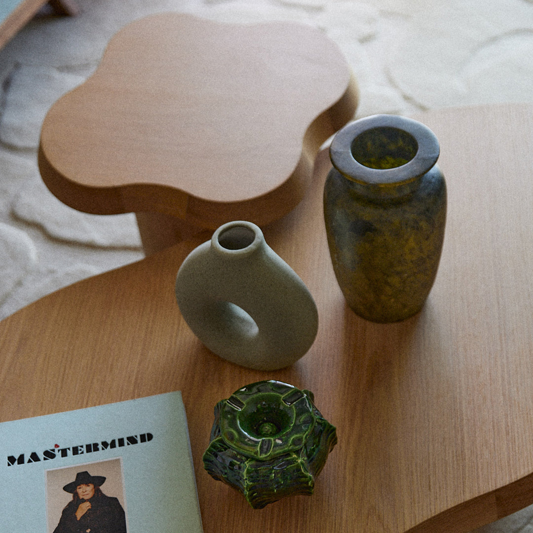 "Three decorative vases: muted gray, vibrant green with marbling, and a textured dark green, displayed on a wooden surface."