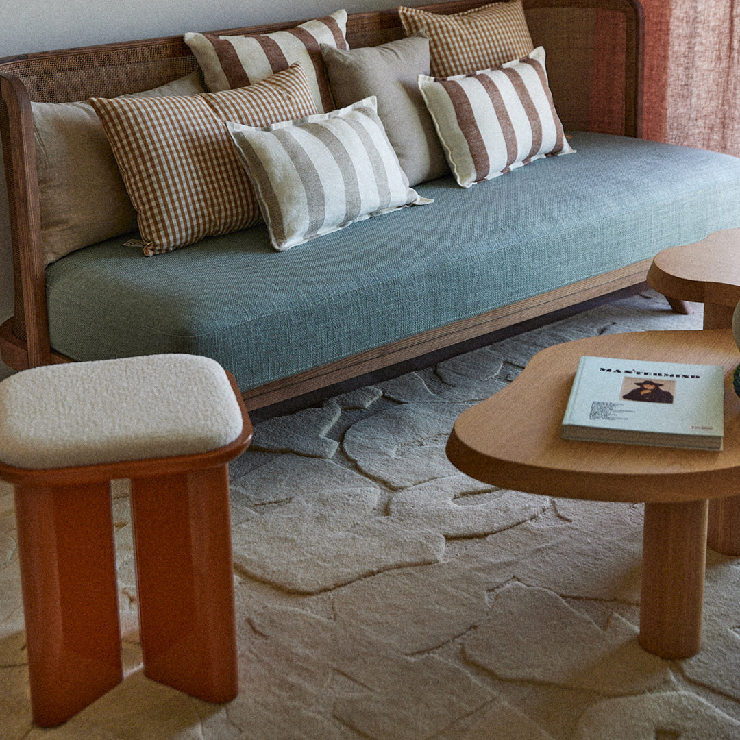 Natural wood tones, muted teal upholstery, and striped beige-and-white cushions create a cozy, modern living space.