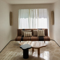 Modern living room with a brown and beige striped sofa, cream pillows, and a black and white patterned coffee table.